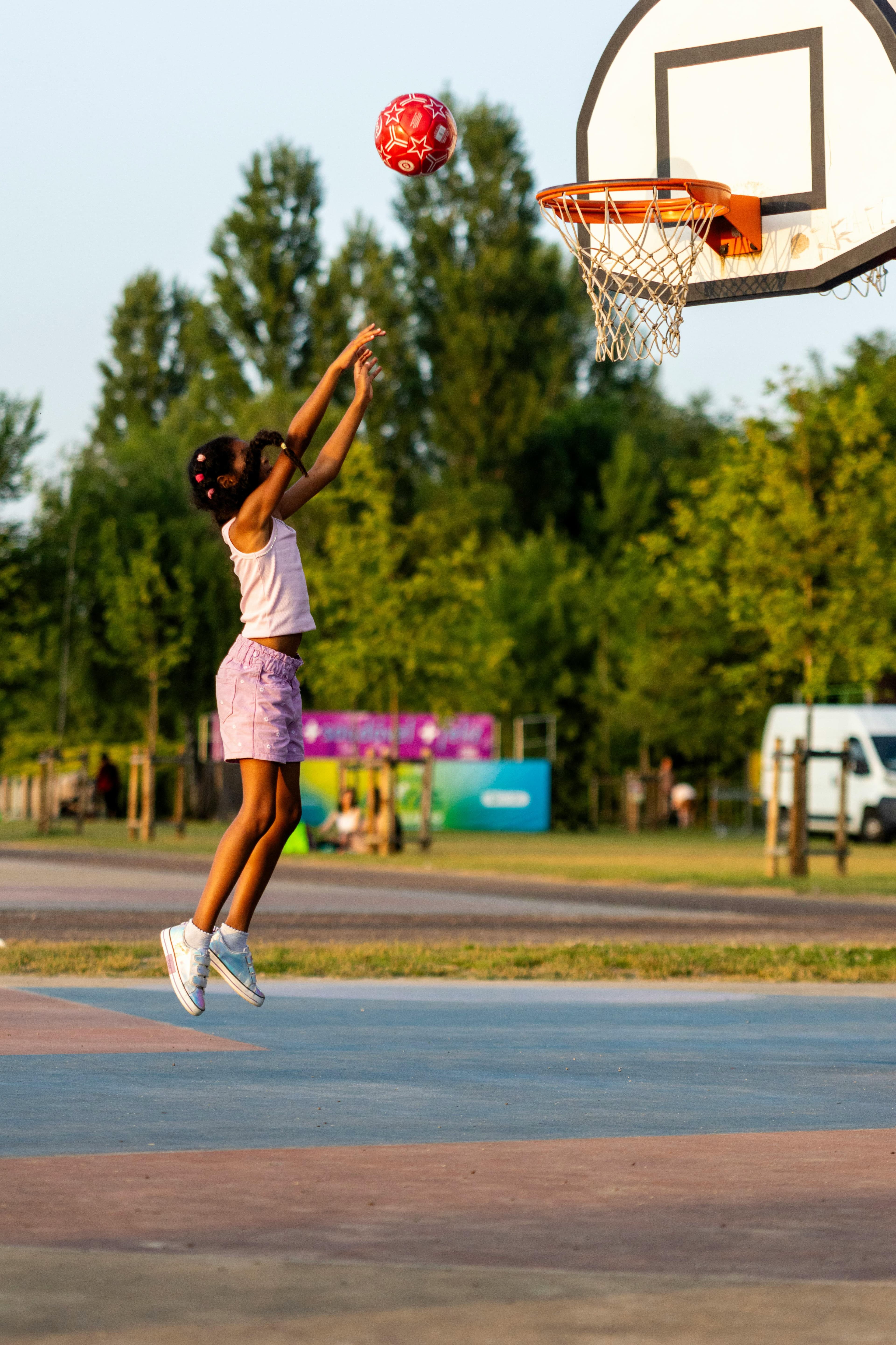 Jeune fille qui saute pour marquer un panier de basket en plein air
